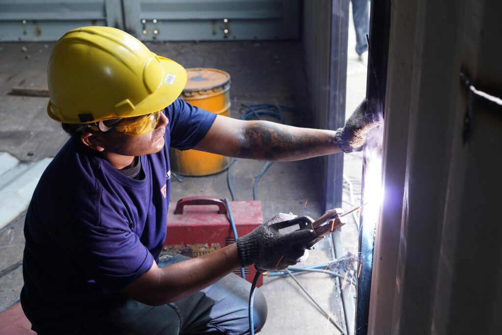 pexels photo 14793021 14793021 A professional welder working indoors with safety helmet and gloves, showcasing skill in metalwork.